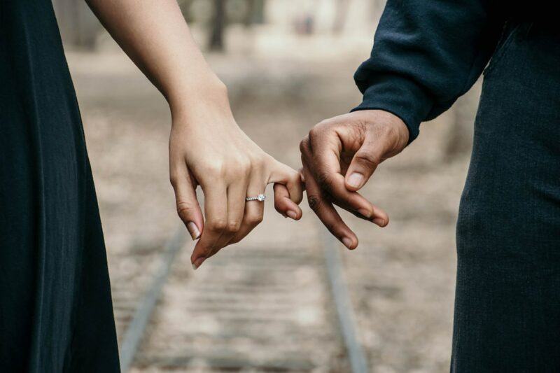 Two hands, one with an engagement ring, and the little fingers entwined. If you want to recreate this photo, you need to know how to propose!