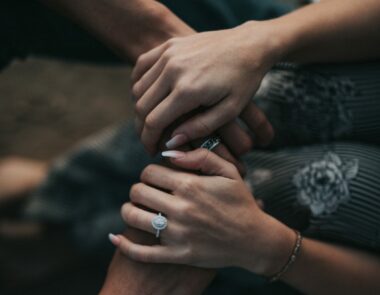 A woman wearing an engagement ring with her hands over a man’s; How to propose to a man.